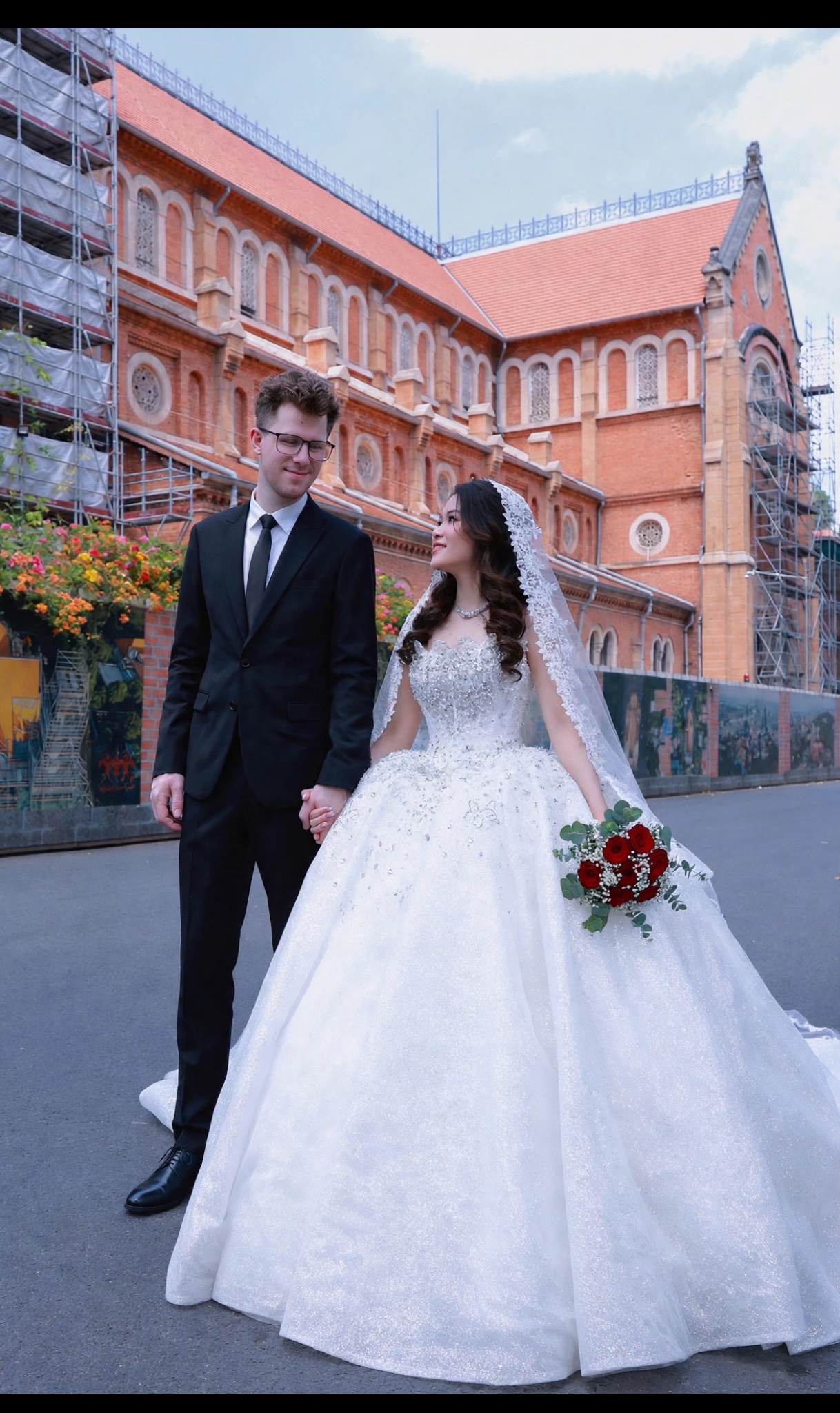 Silas und Thi Khanh Chi Hand in Hand in Hochzeitskleidung